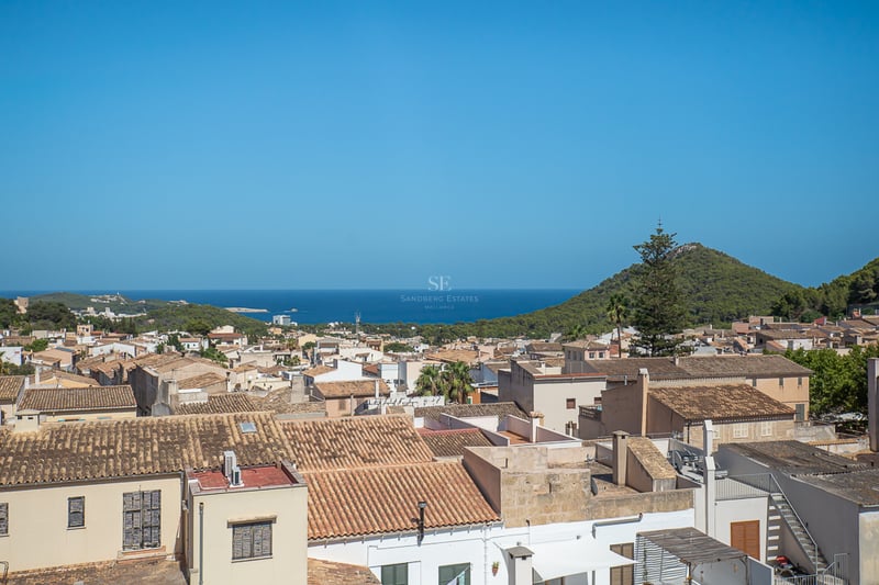 Vue surélevée de toits en terre cuite traditionnels menant à la mer Méditerranée et à une colline verdoyante.