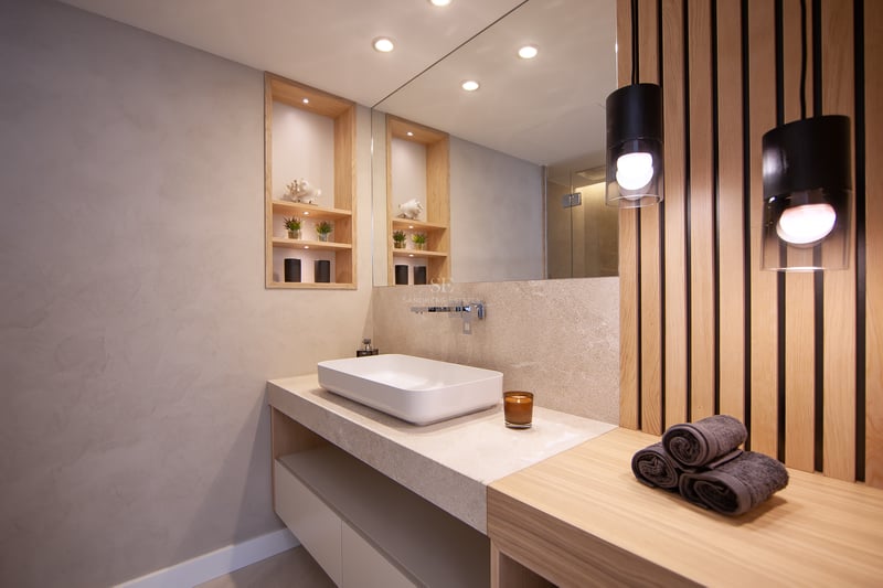 Salle de bain moderne avec vasque à poser, plan de travail en pierre, mur en lattes de bois et éclairage chaleureux.