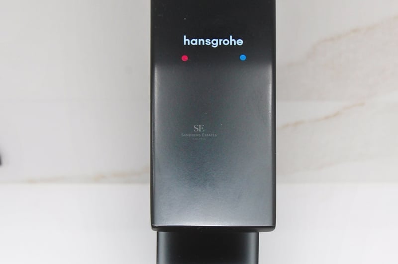 Närbild på en stilren mattsvart Hansgrohe-blandare mot en vit marmorvägg.