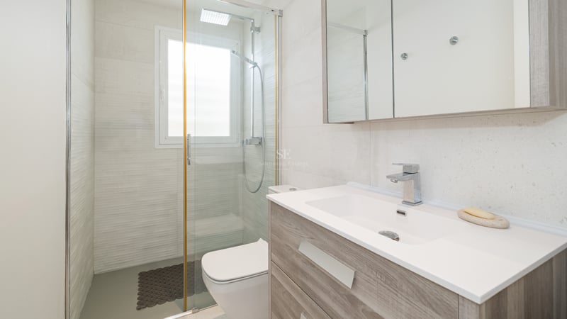 Bright bathroom featuring a wooden vanity, large mirror, and glass walk-in shower.