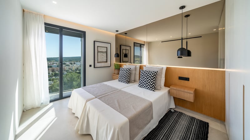 Chambre contemporaine avec lits jumeaux, tête de lit en chêne avec miroir intégré et porte-fenêtre sur terrasse.