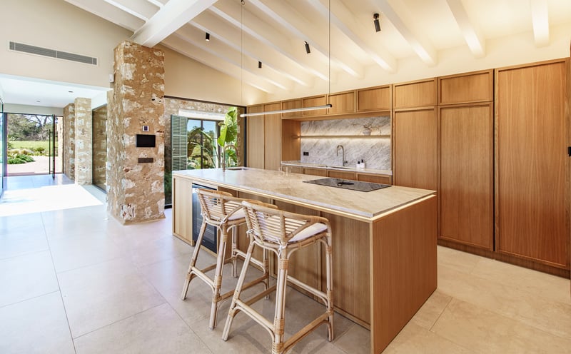 Moderne Küche mit Holzinsel, Marmor-Arbeitsplatte, Rattanhockern und weißer Balkendecke.