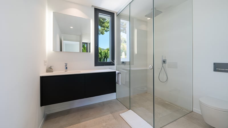 Salle de bains contemporaine avec douche à l'italienne en verre, meuble vasque noir et miroir rétroéclairé.