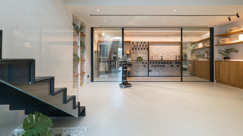 Modern vinkällare i glas med stenvägg, platsbyggda hyllor och minimalistisk trappa i lyxvilla.