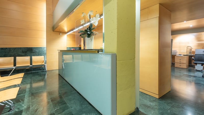 Hall d'entrée moderne avec bureau en verre dépoli, sol en marbre vert et murs en bois clair.