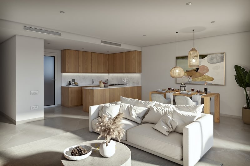 Bright open-plan living space with a white sofa, wooden kitchen cabinets, and a dining area with woven pendant lights.