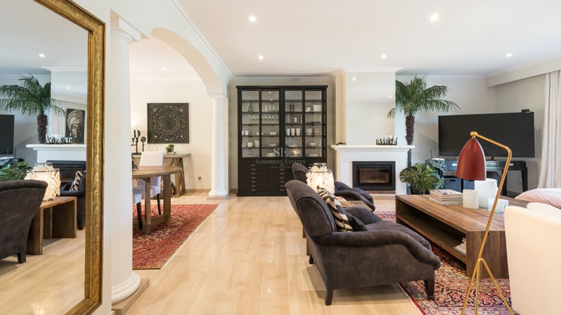 Spacious Mediterranean living room with marble floors, integrated fireplace, classical arches, and luxury furnishings.