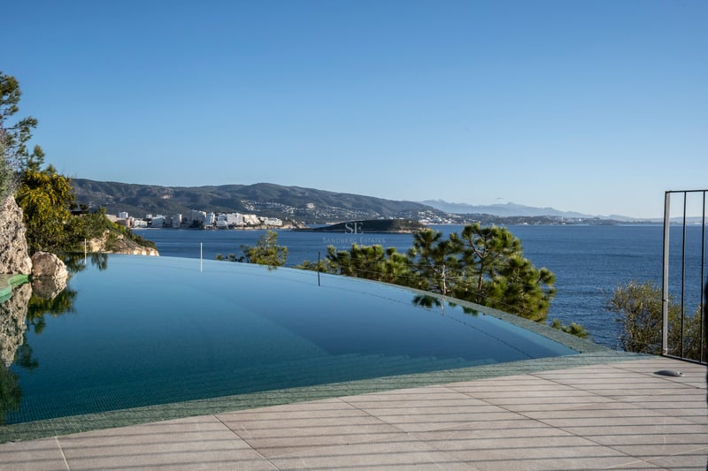 Infinity-Pool mit klarem blauen Wasser und Blick auf das Mittelmeer und die bergige Küste bei Tageslicht.