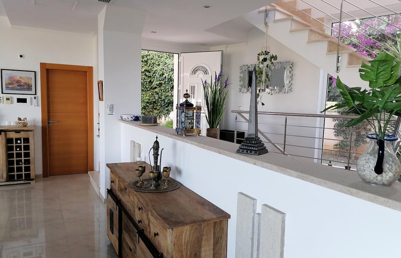 Entrée de villa spacieuse avec sols en marbre poli, buffet en bois et escalier moderne en acier inoxydable.