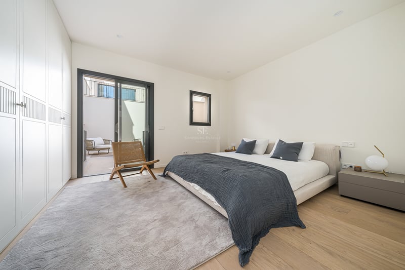 Bright master bedroom featuring floor-to-ceiling wardrobes, light oak floors, and sliding glass doors to a private patio.