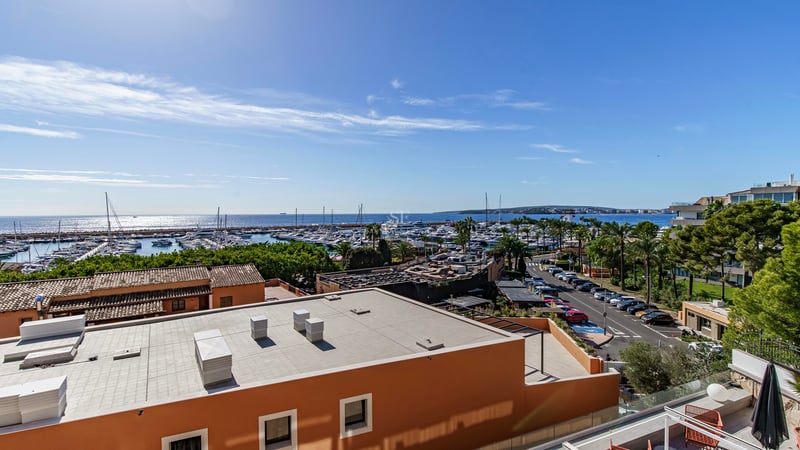Elevated view overlooking a marina with yachts and the Mediterranean sea under a clear blue sky.