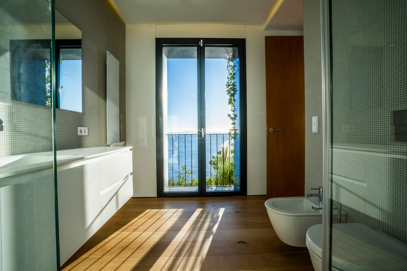 Modernes Badezimmer mit Eichenparkett und bodentiefem Fenster mit Blick auf das Mittelmeer.