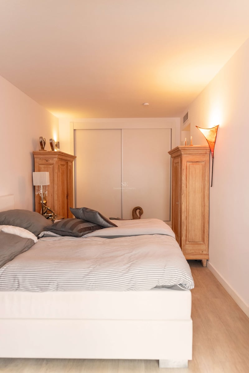 Helles Schlafzimmer mit großem Bett, zwei Holzschränken und Einbauschiebetüren bei warmer Ambientebeleuchtung.