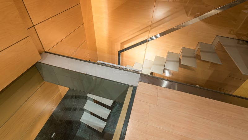 Vue plongeante d'un escalier moderne avec marches en verre et parois en bois chaleureux.