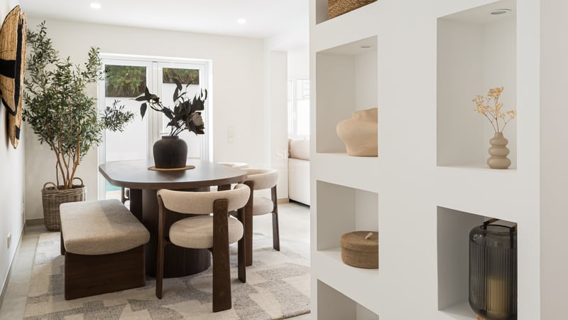 Contemporary dining room featuring a dark wood table, cream chairs, and white built-in wall niches.