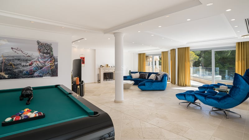 Großer moderner Spielraum mit blauem Sofa, Billardtisch, Steinboden und klassischem Kamin.