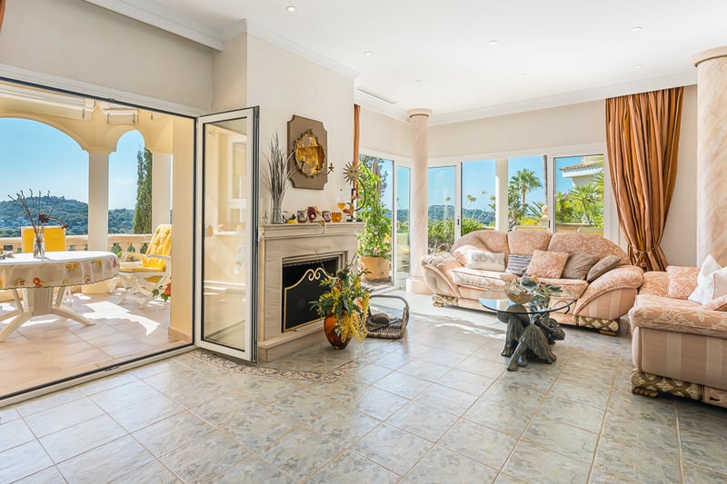 Modern balcony with glass railing, light wood flooring, and panoramic views. Minimalist design with plants and stylish furniture.