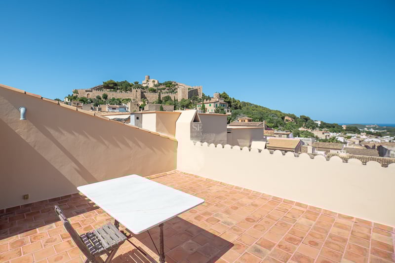 Terrasse sur le toit avec carrelage en terre cuite surplombant un château historique sur une colline verdoyante.