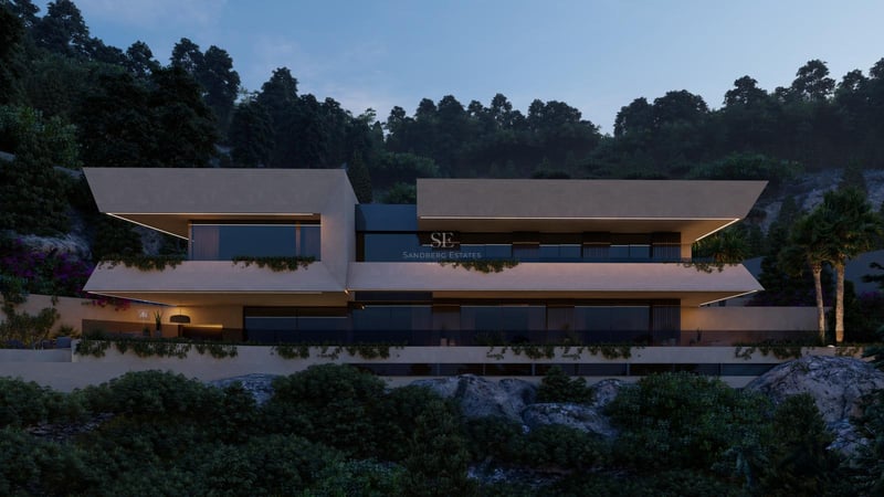 Dusk view of a contemporary multi-level villa with cantilevered balconies and integrated greenery on a rocky hillside.