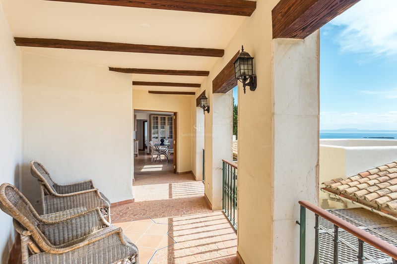 Vue extérieure d'une luxueuse maison avec piscine à débordement, entourée de verdure et présentant une architecture moderne et minimaliste.