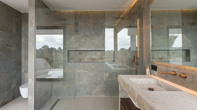 Zeitgenössisches Badezimmer mit grauen Steinfliesen, Glasduschwand und Waschtisch aus Naturstein.