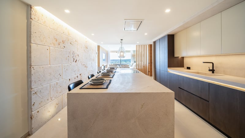 Cuisine contemporaine avec un grand îlot en pierre, des armoires en bois sombre et un mur en pierre naturelle.