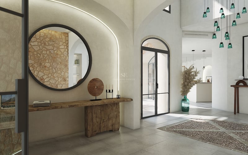 Entrée de villa spacieuse avec arches, mur en pierre naturelle, miroir rond et console en bois sculpté.