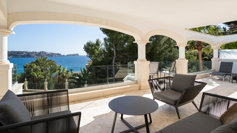 Überdachte Steinterrasse mit Rundbögen, Glasgeländern und modernen Möbeln mit Blick auf das Mittelmeer.