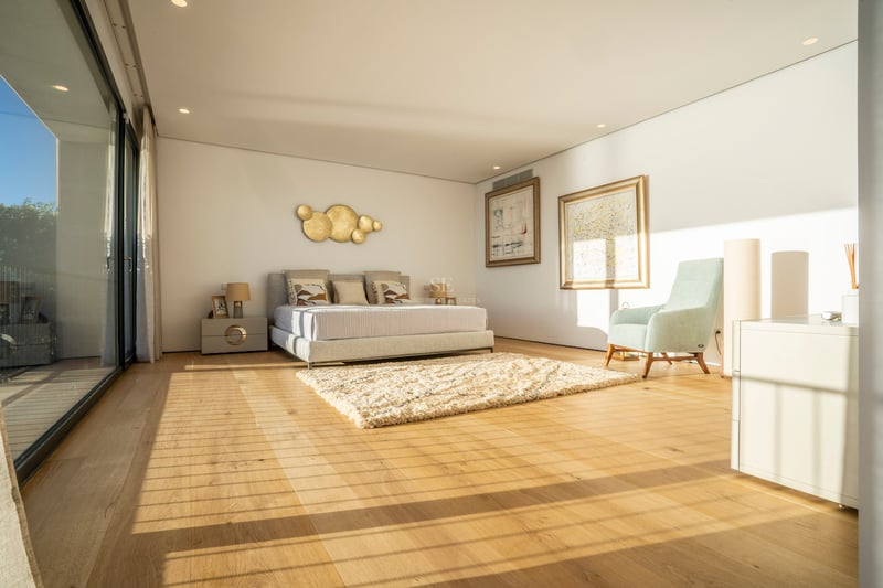 Helles, modernes Hauptschlafzimmer mit Eichenparkett, bodentiefen Glastüren und zeitgenössischen Möbeln.