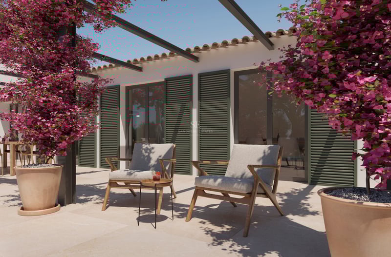 Terrasse en pierre avec deux fauteuils en bois, volets verts et bougainvilliers roses éclatants sous un ciel clair.