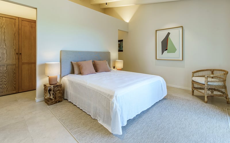 Helles Hauptschlafzimmer mit Gewölbedecke, Nachttischen aus Naturholz und Textilien in neutralen Tönen.