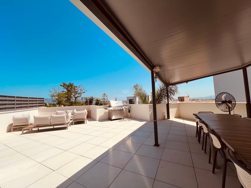 Grande terrasse moderne sur le toit avec barbecue en inox, coin repas et salon d'été sous une pergola.
